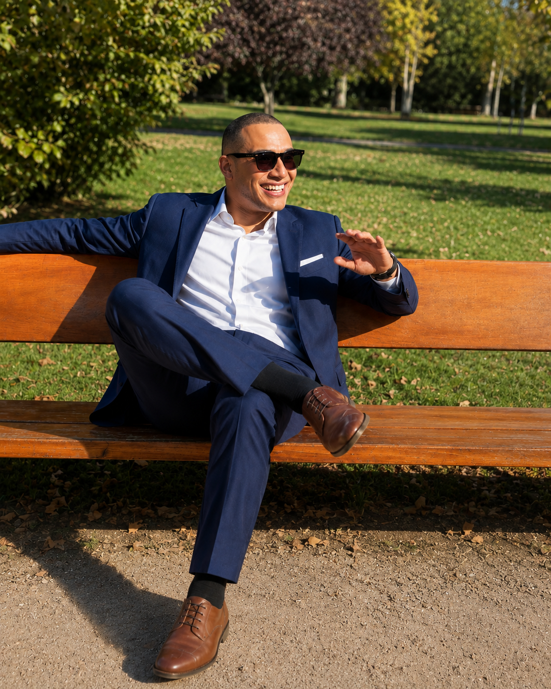 Jorge Faulkner seated on a park bench in a navy suit, smiling